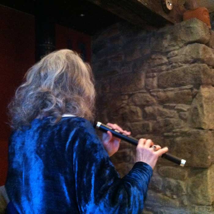 Nan playing flute in the stone walled living room